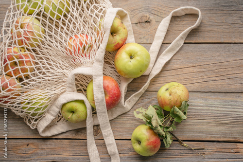 fresh apples in an eco string bag on a wooden background. natural products. zero waste.