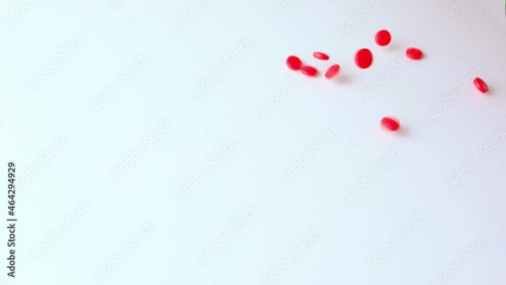 red pills, medicine falling on the table from above, bouncing, scattering, slow motion, concept development, production, sale of drugs, vitamins, pharmaceutical products