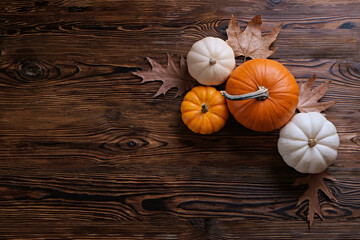 Bunch of pumpkins of different kinds, shapes and colors on wooden background as a symbol of autumnal holidays with a lot of copy space for text.
