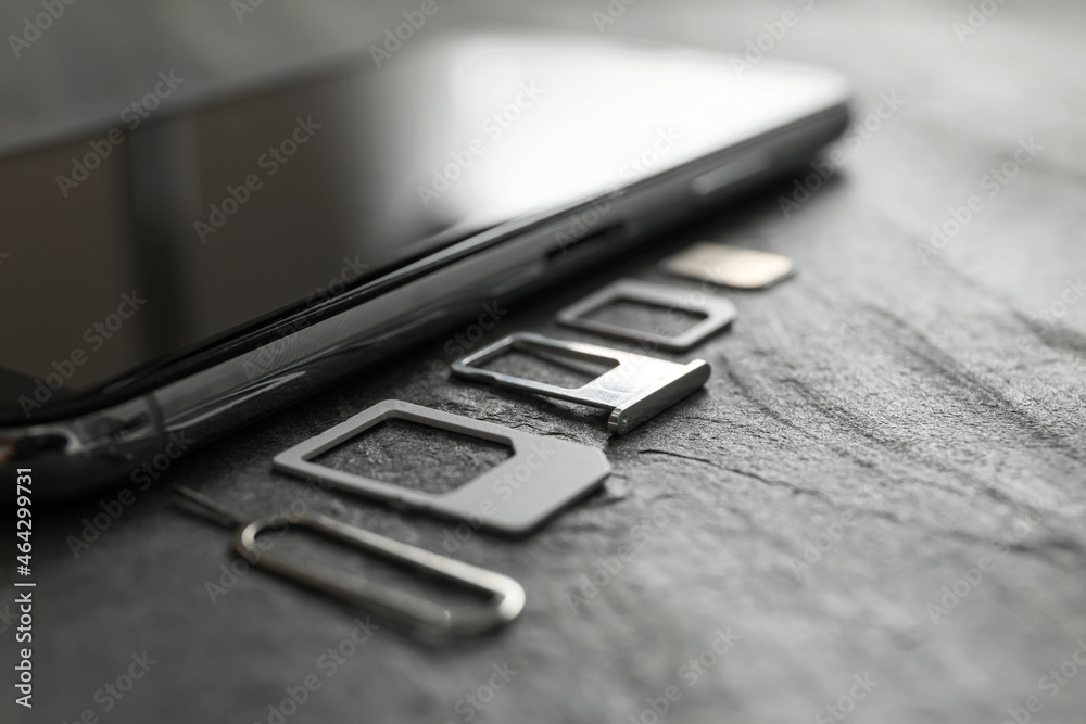 SIM card, mobile phone and ejector tool on grey table, closeup SIM card, mobile phone and ejector tool on grey table, closeup