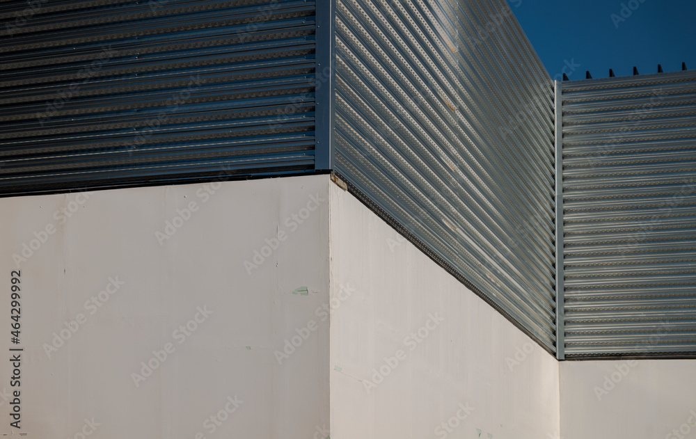 Closeup of white wall and metal wall against blue sky