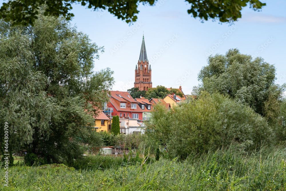 Landscape of Röbel Müritz when looking at the city center. The tower of the church is visible at the horizon. A skyline of a small town in Germany surrounded by green nature. Architecture in Europe.