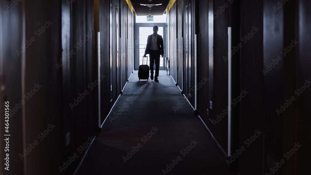 businessman with suitcase walking along hotel corridor. businessman with suitcase walking along hotel corridor.
