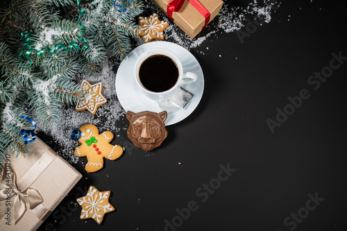 Christmas and New Year decoration composition. Top view of fur-tree branches on dark background with place for your text. Cups of fragrant coffee with gingerbread and chokolate.