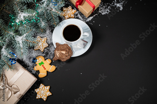 Christmas and New Year decoration composition. Top view of fur-tree branches on dark background with place for your text. Cups of fragrant coffee with gingerbread and chokolate.