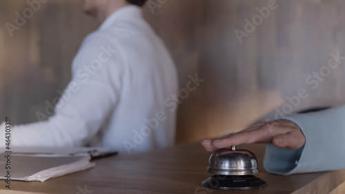cropped view of client pressing service bell near hotel receptionist.