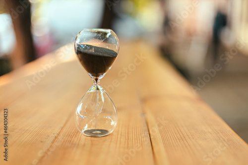 Hourglass on wooden table outdoors in the rays of sunlight. Business deadline concept