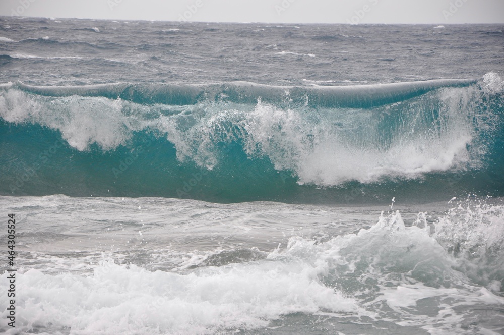 Rolling wave crashing on rocky coast.wave breaking on the shore.A big wave overlaps the coast of the Croatian island of Losinj. Rolling wave crashing on rocky coast.wave breaking on the shore.A big wave overlaps the coast of the Croatian island of Losinj.