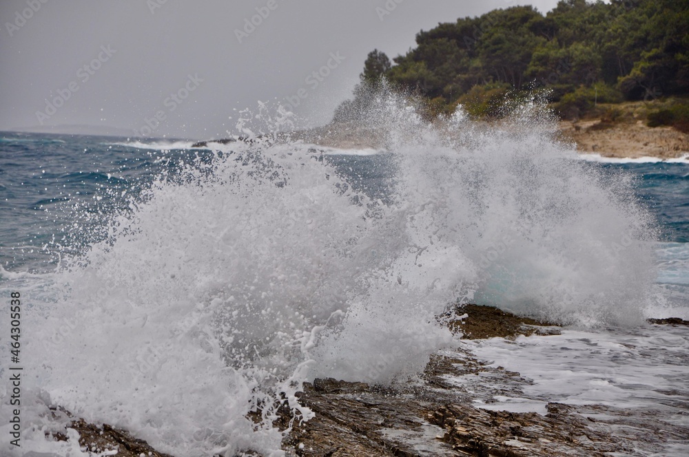 Big wave splash into croatian rocky beach during strong wind on Adriatic Sea. Horizon line.