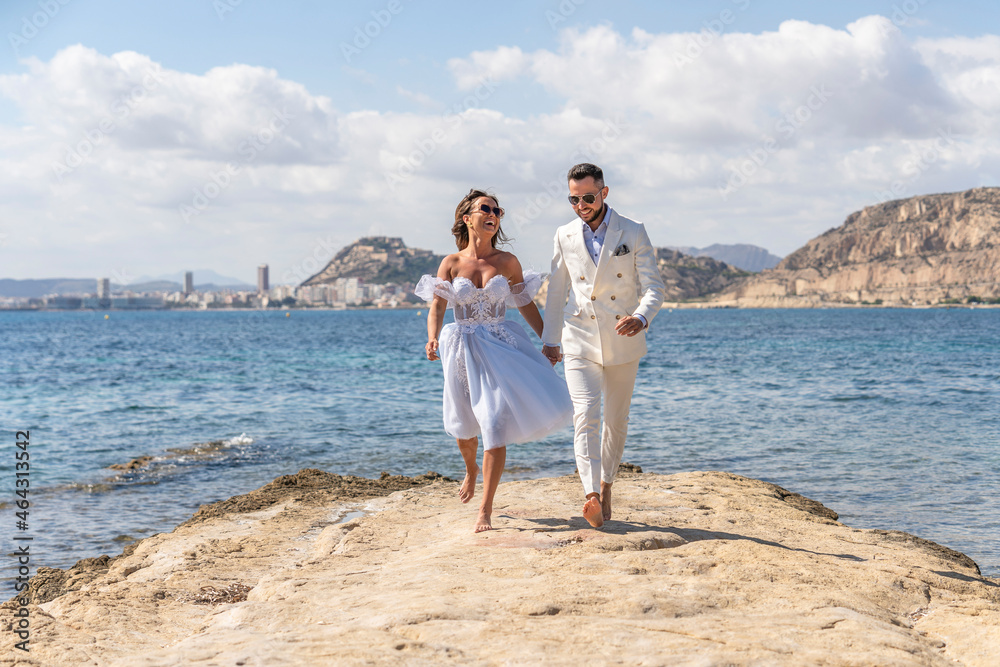Carefree wedding couple running on coast Carefree wedding couple running on coast