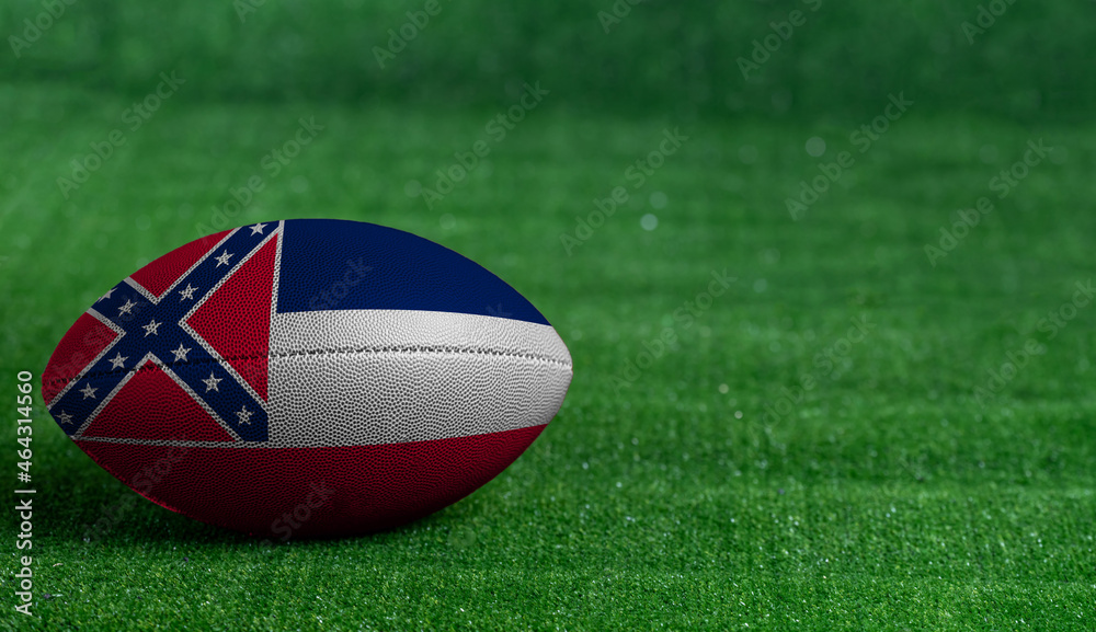 American football ball with Mississippi flag on green grass background, close up American football ball with Mississippi flag on green grass background, close up