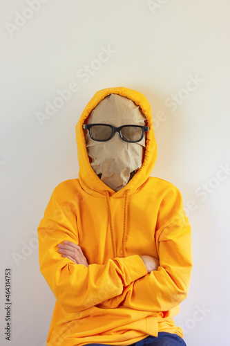 unknown person in paper mask and glasses for the cinema on the face in a yellow hoodie and a hood on the head. concept without a face, a person of invisibility, faceless.