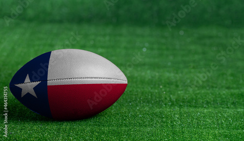 American football ball  with Texas flag on green grass background, close up