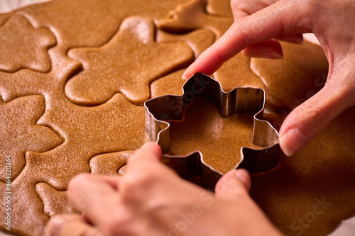 Obraz na plátně cutting gingerbread man dough with aluminum molds