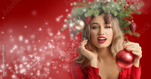Beautiful young woman with Christmas wreath on color background