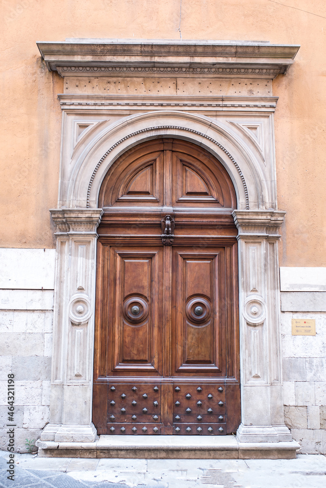Vintage front door in the medieval city of Italy. Ancient streets of the city, beautiful doors and unusual door handles in the shape of a lion's head.