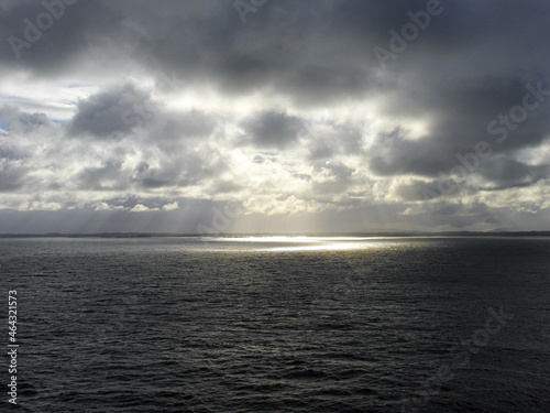 Sonne scheint durch dunkle Regenwolken   ber dem Meer