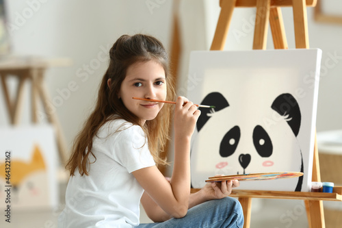 Cute little girl painting a...