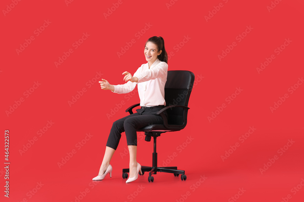 Young woman with imaginary steering wheel sitting in chair on color background Young woman with imaginary steering wheel sitting in chair on color background