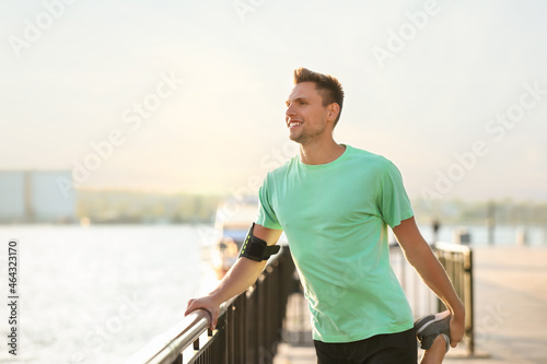 Sporty young man stretching near river