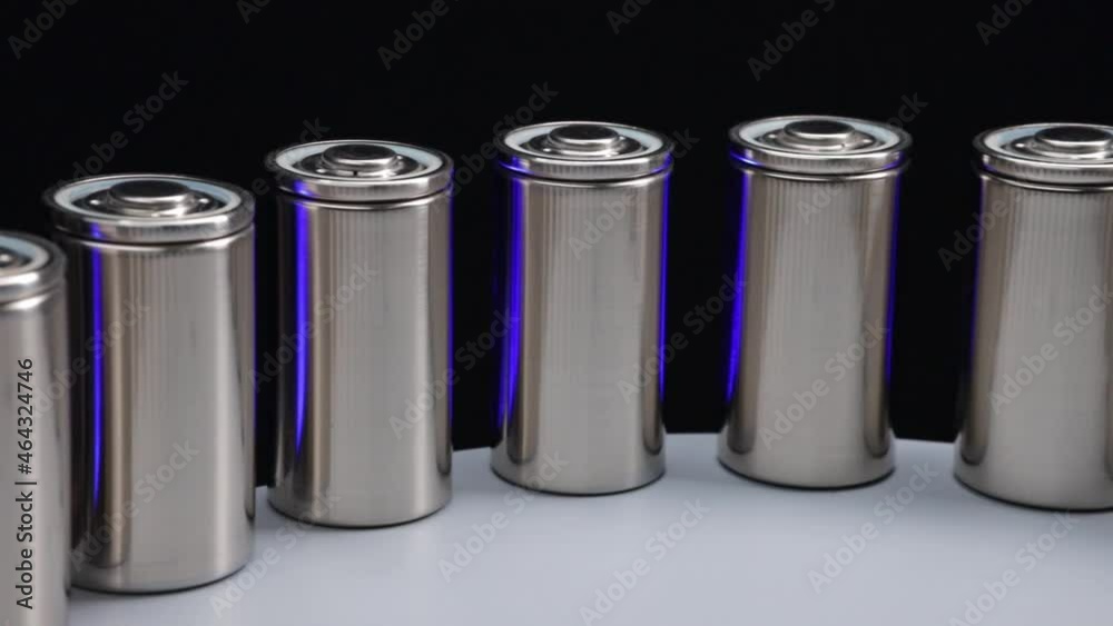 Closeup of manufacture of new high-capacity lithium batteries on a production line with flashing blue backlight on the black background

