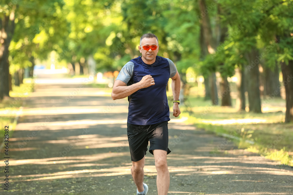 Sporty mature man with eyeglasses jogging in park Sporty mature man with eyeglasses jogging in park