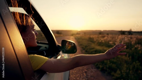 Happy girl in car window. Hair in wind. Girl travels by car. Hand in sun. Windy breeze from car window. Happy girl smiling from car window. Windy breeze in your hair. Hand in the rays of the sun photo