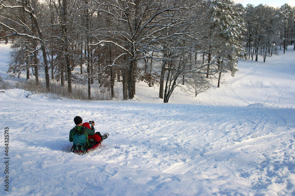 Father and Child Piled on Sled Take Selfie As They Slide Down a Snowy Hill