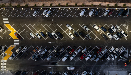 Drone aerial view of parking lots with cars at night. Crowded shopping mall car park.