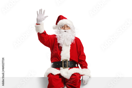 Foto Cheerful santa claus sitting on a panel and waving