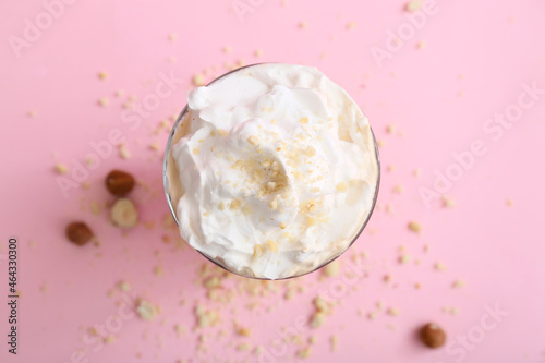 Glass of tasty latte with nuts on pink background