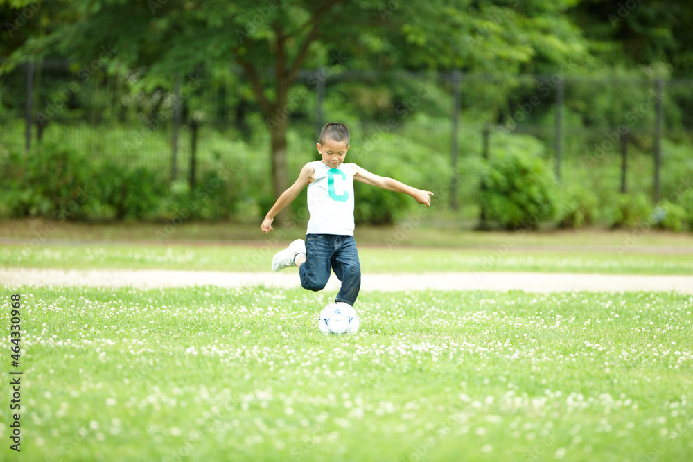 緑の芝生の上で元気よくサッカーをして遊ぶ男の子 緑の芝生の上で元気よくサッカーをして遊ぶ男の子