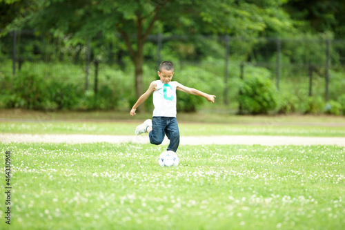 緑の芝生の上で元気よくサッカーをして遊ぶ男の子 photo