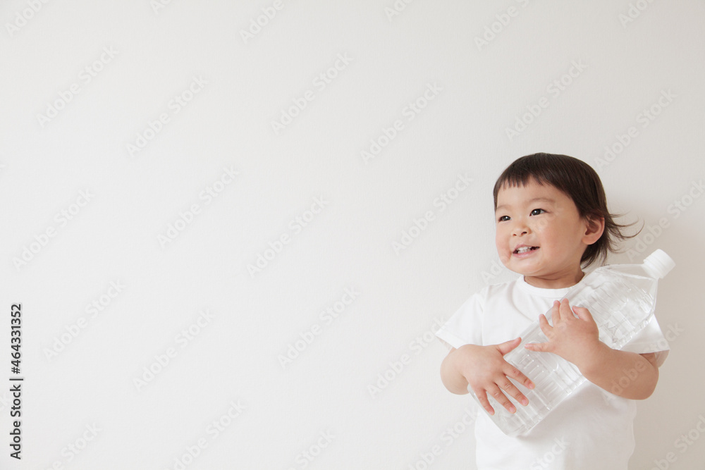 水のペットボトルを持って遠くを見つめる子供 水のペットボトルを持って遠くを見つめる子供