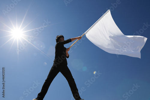 青空と太陽の下で白い旗を振る男性 photo