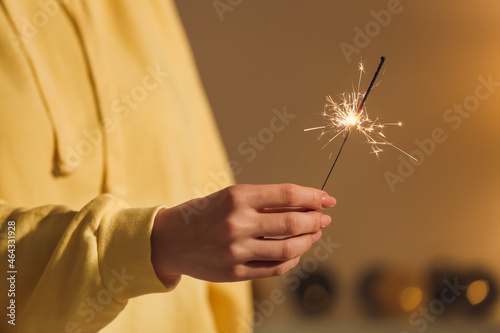 Woman with sparkler in room, closeup