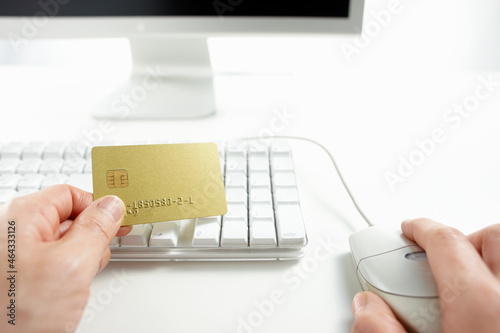 クレジットカードを持ってネットショッピングをしている男性の手 photo
