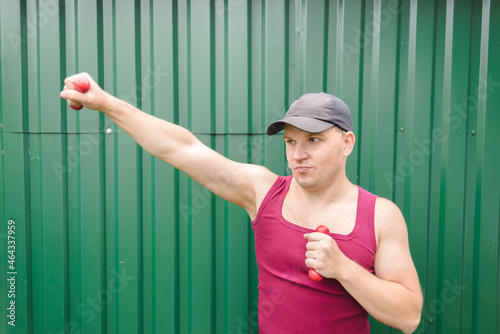 Young man is exercising with dumbbells.