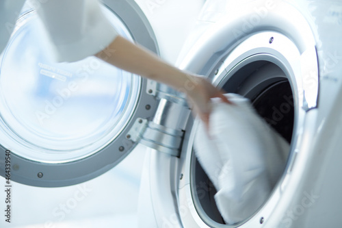 ドラム式洗濯機に洗濯物を入れる女性の手 photo