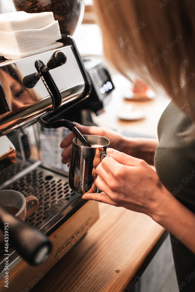 Closeup image of hands pouring milk and preparing fresh cappuccino, coffee artist and preparation concept, morning coffee