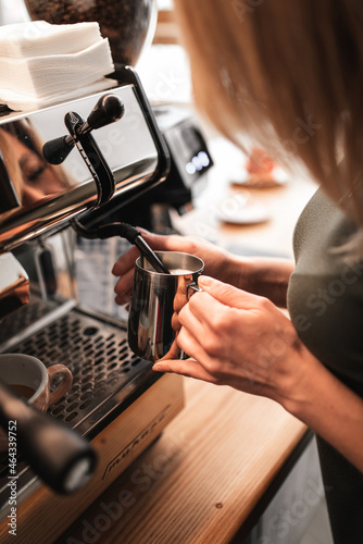 Closeup image of hands pouring milk and preparing fresh cappuccino, coffee artist and preparation concept, morning coffee