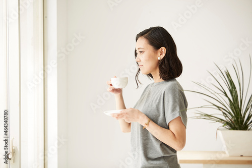 窓辺にたたずみコーヒーを飲む女性 photo