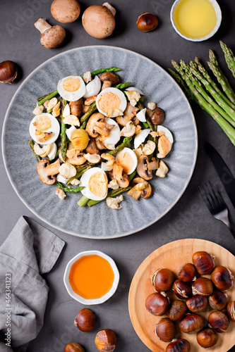 Salad with chestnuts, mushroom, asparagus and eggs on grey stone background, top view, autumn dish, flat lay, copy space
