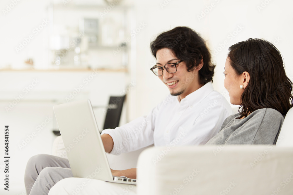 リビングのソファーでパソコンを見ている男女