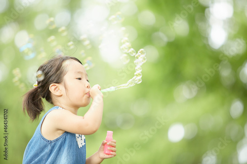 自然の中でシャボン玉を吹いて遊ぶ女の子