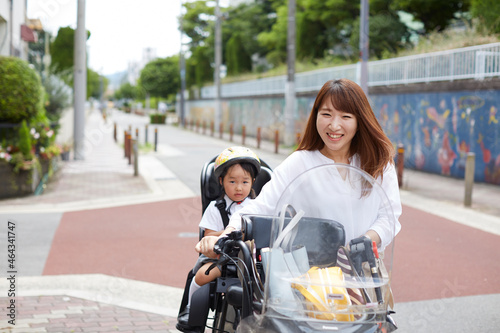 子供を乗せた自転車を押して歩く母親 photo