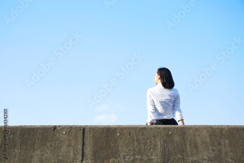 堤防に座る女子高生の後ろ姿 photo