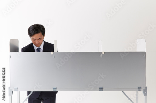 投票記載台を使用しているスーツを着た男性