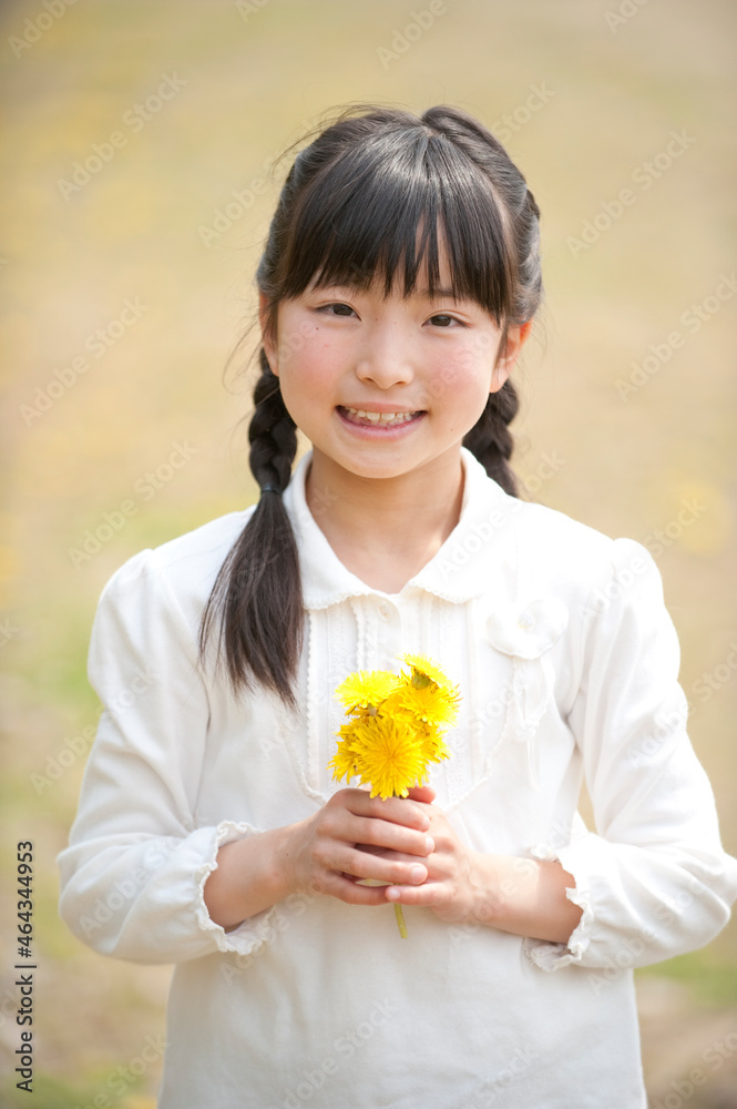 タンポポの花を持って微笑む女の子