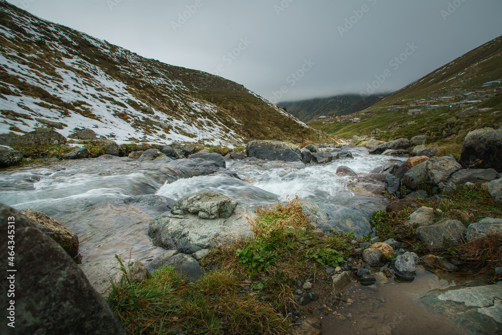 Fast flowing river from a mountain range. Close up of river stones with flowing water Fast flowing river from a mountain range. Close up of river stones with flowing water